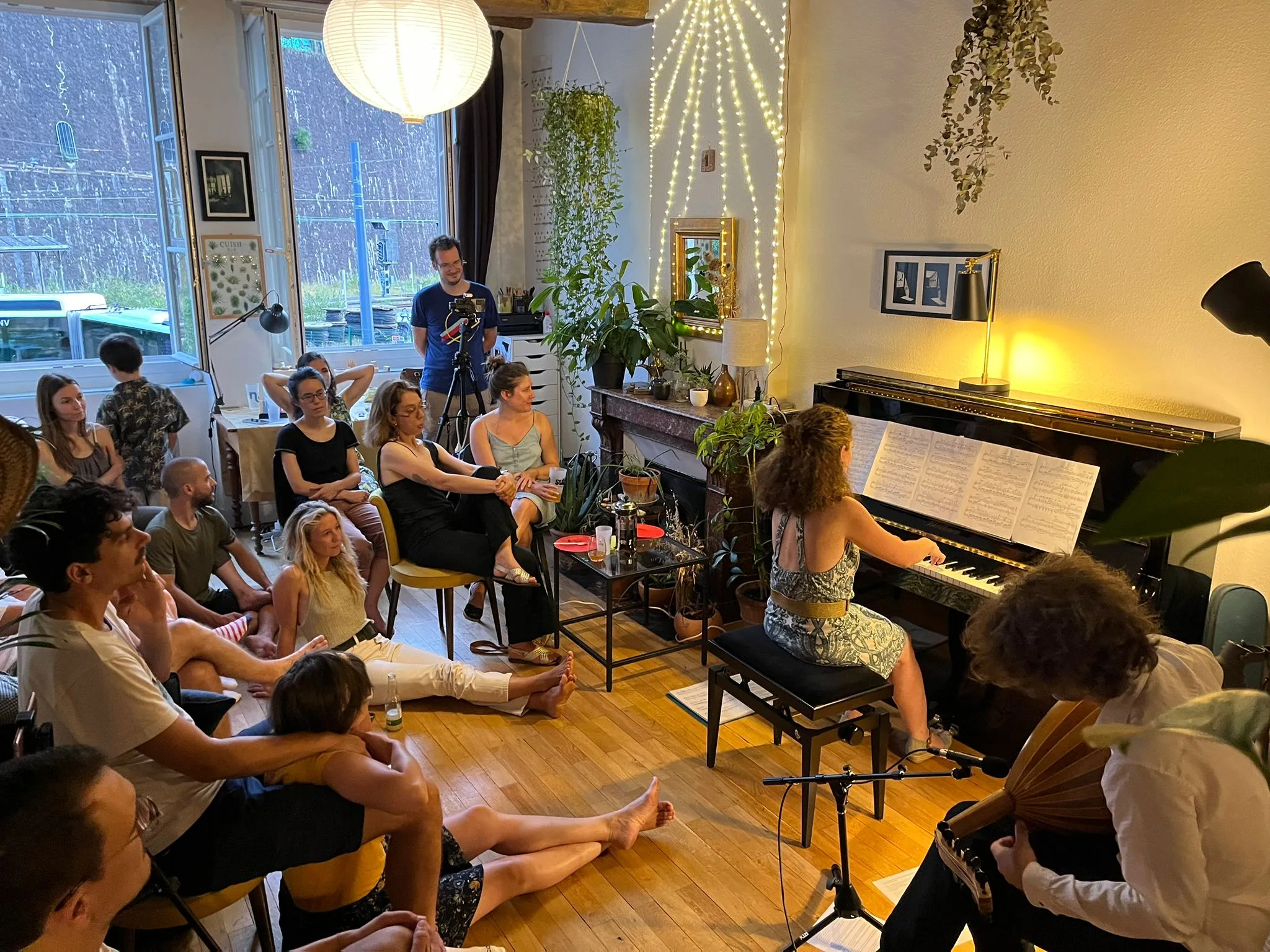 Un concert dans un appartement à Lyon avec les spectateurs assis par terre ou sur des chaises, écoutant une pianiste et un joueur de Oud.